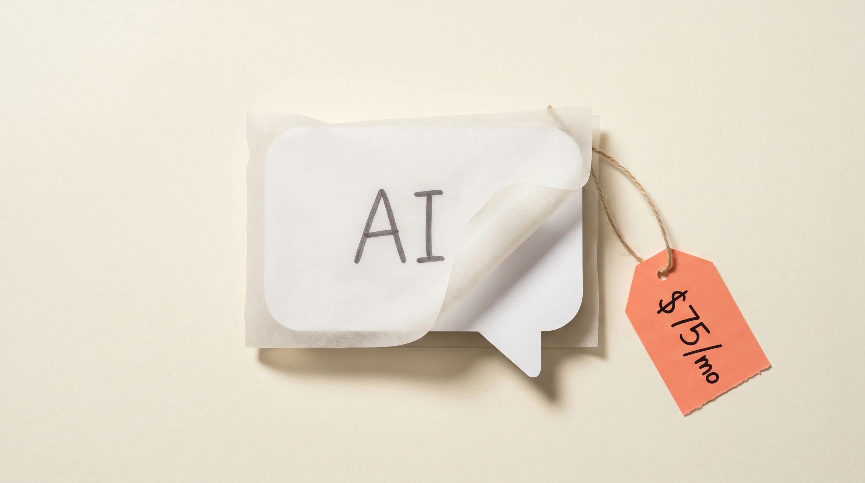 Paper-craft overhead scene: a translucent vellum wrapper labelled AI loosely draped over a plain white chat-bubble box, with a coral-orange pentagon price tag reading $75/mo dangling on a string