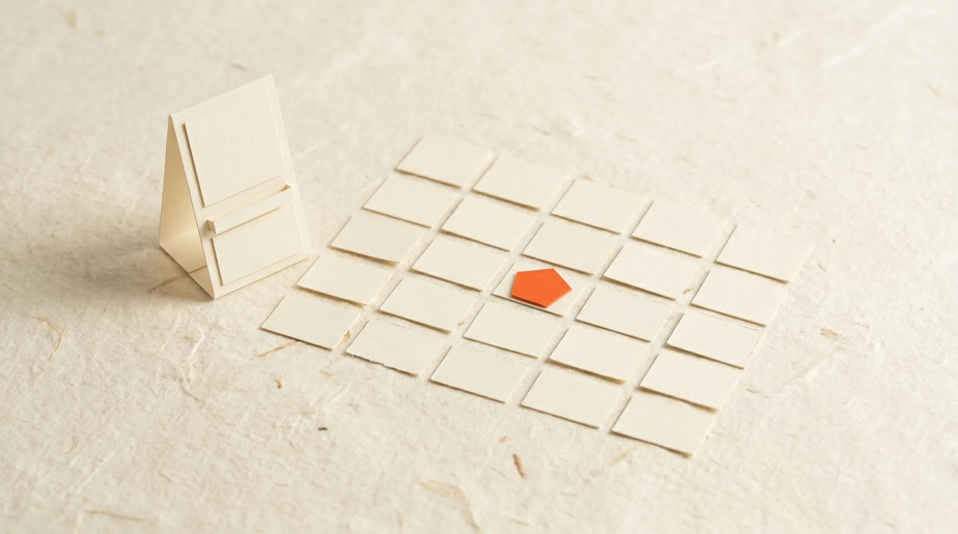 Paper-craft model of a bespoke booking-page kiosk with calendar tiles fanning out beside it on cream paper